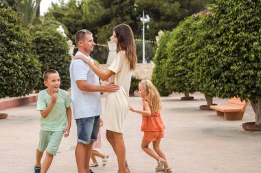 Family spending time together, cheerful parent with kids walking in the park in good weather
