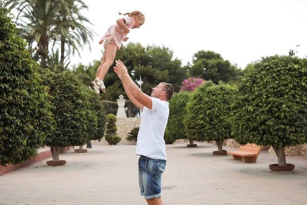 Dad holds his daughter in his arms, a walk in the city park, family leisure