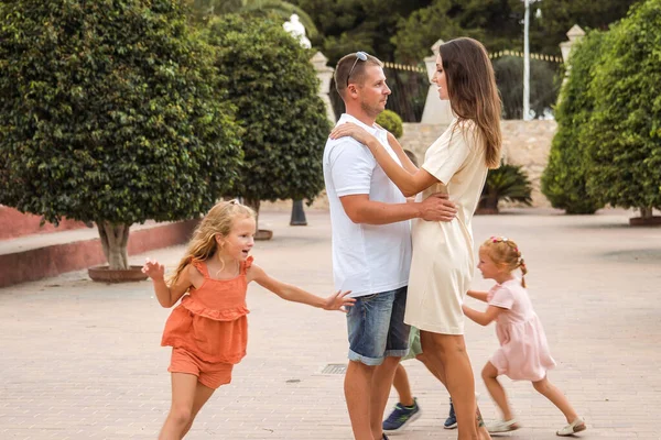 Family spending time together, cheerful parent with kids walking in the park in good weather