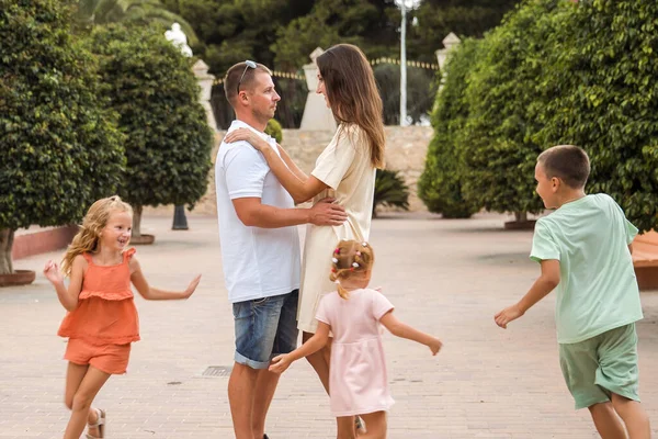 Family spending time together, cheerful parent with kids walking in the park in good weather