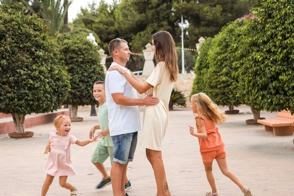 Family spending time together, cheerful parent with kids walking in the park in good weather