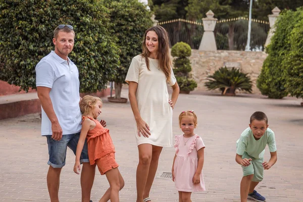 Family spending time together, cheerful parent with kids walking in the park in good weather
