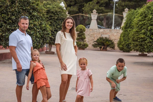 Family spending time together, cheerful parent with kids walking in the park in good weather