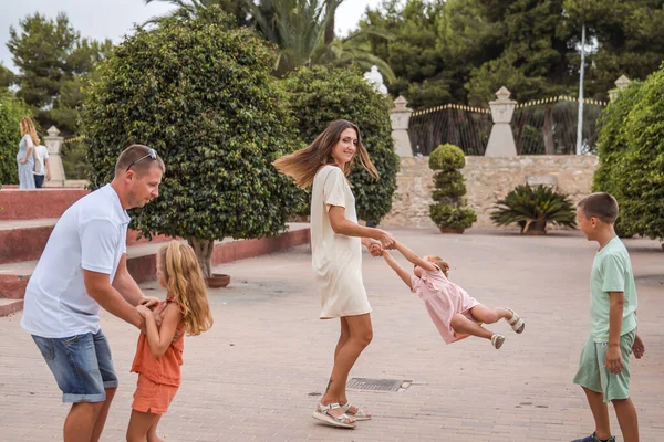 Family spending time together, cheerful parent with kids walking in the park in good weather