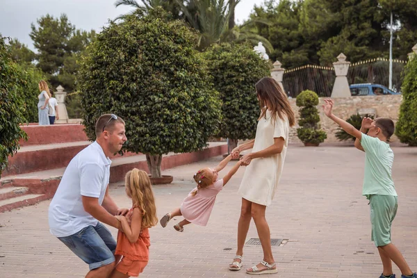 Family spending time together, cheerful parent with kids walking in the park in good weather