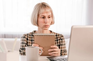 Business Woman listening educational lecture on computer, watching webinar, studying on online courses, writing notes in paper copybook, e-learning concept