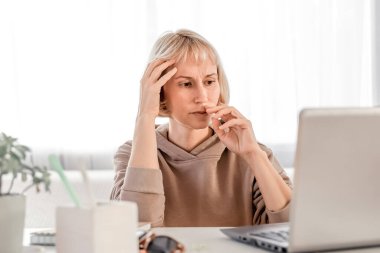 Business Woman listening educational lecture on computer, watching webinar, studying on online courses, writing notes in paper copybook, e-learning concept
