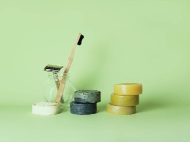Bamboo toothbrush, steel razor and six natural soaps against green background. clipart