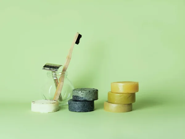 Escova de dentes de bambu, lâmina de aço e seis sabonetes naturais contra fundo verde. Imagens De Bancos De Imagens Sem Royalties
