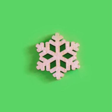 Yeşil arka planda el yapımı ahşap kar tanesinin yukarıdaki görüntüsü.