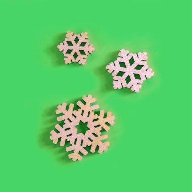 Yukarıdaki manzara yeşil arka planda üç el yapımı ahşap kar tanesi..