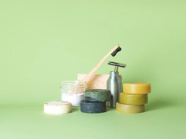 Bamboo toothbrush, steel razor and six natural soaps against green background. — Stock Photo, Image