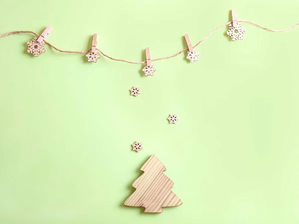 Five handmade wooden snowflakes on the rope with pegs on the green background. — Stock Photo, Image