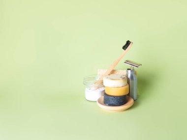 Bambu diş fırçası, çelik ustura ve yeşil arka plana karşı üç doğal sabun..