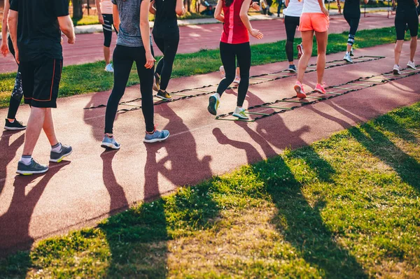 Ladder Drills. Team training outdoors on an athletic track. Female running training in nature, warm sunset light