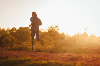 Kenya 'daki Iten şehrinin yakınlarındaki kırmızı toprak yolda koşan Kenyalı bir koşucunun silueti. Uzun pist ve maraton koşucuları için atletik spor fotoğrafı