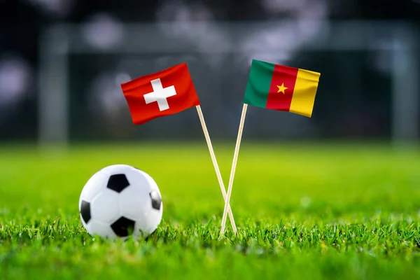 Switzerland vs. Cameroon, Al Janoub, Football match wallpaper, Handmade national flags and soccer ball on green grass. Football stadium in background. Black edit space.