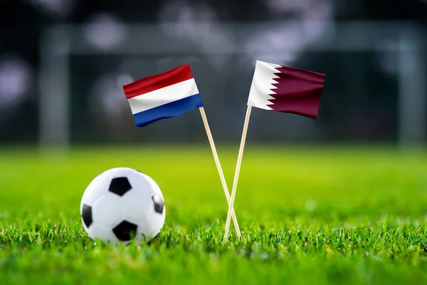 Netherlands vs. Qatar, Al Bayt, Football match wallpaper, Handmade national flags and soccer ball on green grass. Football stadium in background. Black edit space.