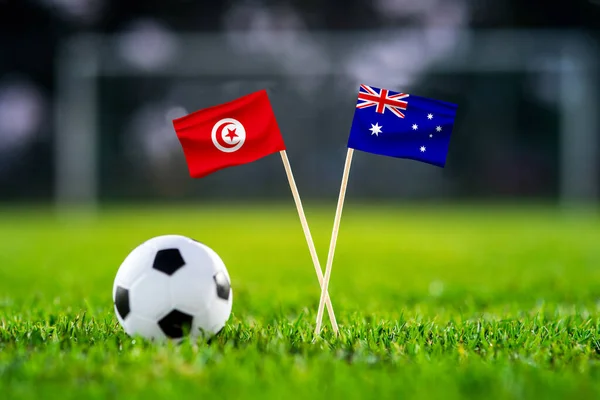 October 2022: Tunisia vs Australia, Al Janoub Stadium, Football match wallpaper, Handmade national flags and soccer ball on green grass. Football stadium in background. Black edit space.