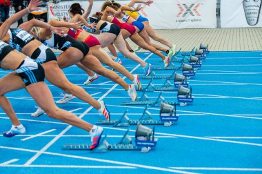 SAMORIN, SLOVAKIA, 9. JULY: Start of female sprint race. Professional Track and Field event. Start blocks and legs of female athletes. Sprint on blue running track