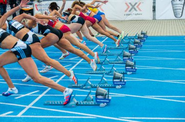 SAMORIN, SLOVAKIA, 9. JULY: Start of female sprint race. Professional Track and Field event. Start blocks and legs of female athletes. Sprint on blue running track clipart