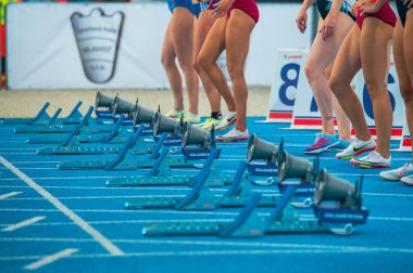 SAMORIN, SLOVAKIA, 9. - Kadın sprint yarışının başlangıcı. Profesyonel Koşu ve Saha etkinliği. Kadın sporcuların başlangıç blokları ve bacakları. Mavi koşu yolunda sürat