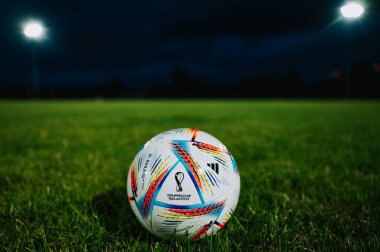 QATAR, DOHA, 18 JULY, 2022: Official Adidas Fifa World Cup Football Ball Al Rihla. World Championship in Qatar 2022. Soccer Match Ball on green grass in night at Stadium. FIFA 22, black edit space.