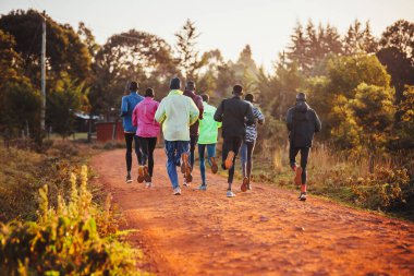 Morning running training in Kenya. A group of endurance runners run on red soil at sunrise. Morning running motivation for training.