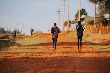 Kenya 'da koşu eğitimi. Bir grup Kenyalı koşucu bir maratona hazırlanıyor ve kırmızı toprakta koşuyorlar. Maraton koşusu, Koşu ve Saha. Kenya 'da basit bir spor hayatı. Eğitim ve egzersiz için motivasyon.