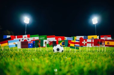 Futbol topu ve yeşil çimlerde 32 ulusal bayrak