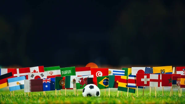 All 32 flags and football ball on green grass. Soccer Tournament