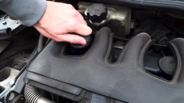 Mühendis bir araba servisinde motor yağını kontrol eder ve tamir eder.