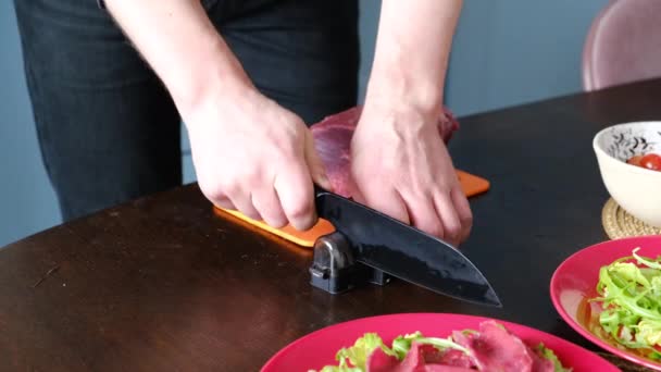 Muž nabrousil nůž, aby nakrájel jídlo na speciální ostří. — Stock video