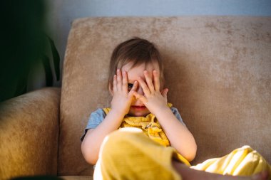 Komik küçük çocuk eğleniyor, evdeki kanepede yumuşak oyuncaklarla oynuyor..