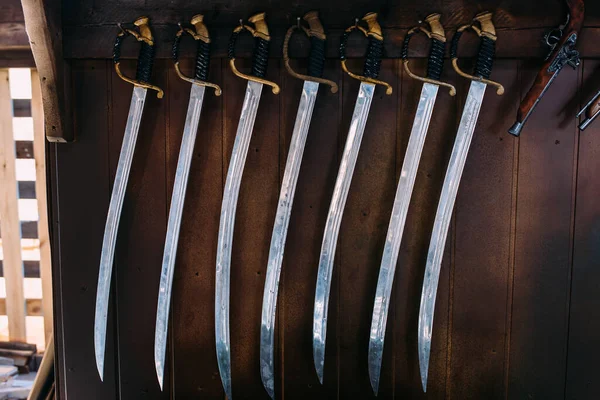Um conjunto de espadas antigas nas prateleiras das lojas de souvenirs. Arma de sabre medieval — Fotografia de Stock