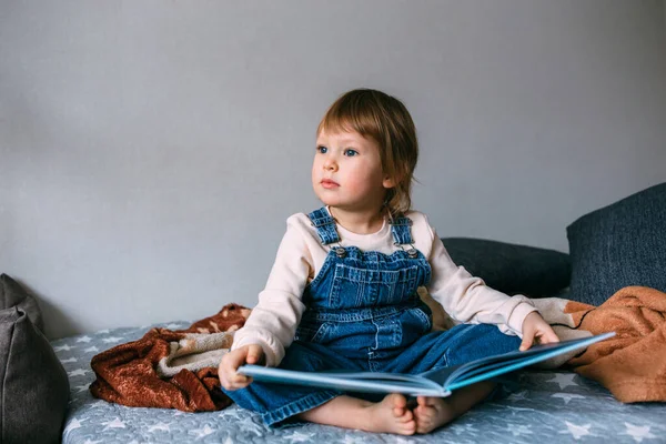 Çocuk evde en sevdiği kitabı okuyor. Çocuk masallardaki resimlere bakıyor.. — Stok fotoğraf