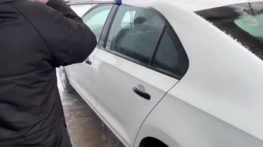 Kadın oto yıkamada araba yıkıyor. Etkin köpükle temizleme