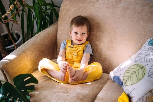 Весела маленька дитина розважається, граючи з м'якими іграшками на дивані вдома . — стокове фото