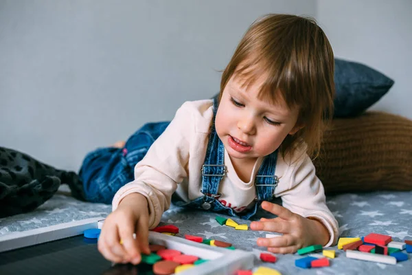 Çocuk evde çok renkli bir manyetik bulmacayla eğitici bir oyun oynuyor
