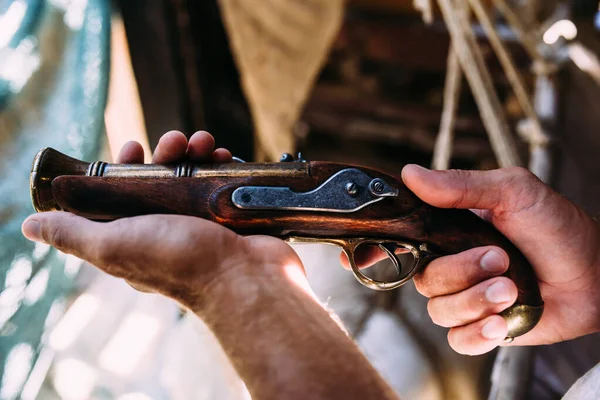 Старый пистолет с деревянной рукояткой в мужских руках. Средневековое оружие — стоковое фото