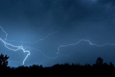 Yaz fırtınası sırasında elektrik boşalımı, gece gökyüzünde dallanmış yıldırımlar..