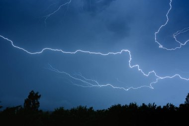 Yaz fırtınası sırasında elektrik boşalımı, gece gökyüzünde dallanmış yıldırımlar..