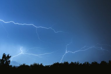Yaz fırtınası sırasında elektrik boşalımı, gece gökyüzünde dallanmış yıldırımlar..