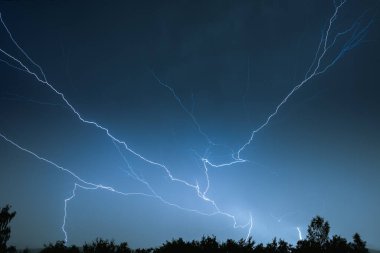 Yaz fırtınası sırasında elektrik boşalımı, gece gökyüzünde dallanmış yıldırımlar..