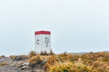 Polonya-Çek sınırındaki sınır işareti, soğuk ve sisli bir günde yürüyüş yolu boyunca duruyor..