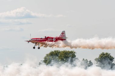 Leszno, Polonya - 17 Haziran 2022: Antidotum Airshow Leszno, Zelazny Aerobatic Team, Zlin 50LS. Pilot, uçağın arkasında muhteşem bir duman bırakarak havaalanı üzerinde alçaktan uçuyor..