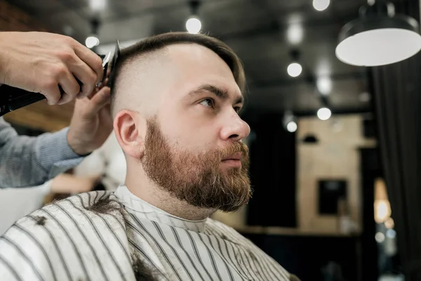 handsome man gets a haircut in a barbershop. Hipster hairstyle concept.