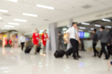 Blurred background of steward sand stewardesses in uniform walking with suitcases at passenger terminal at the airport.