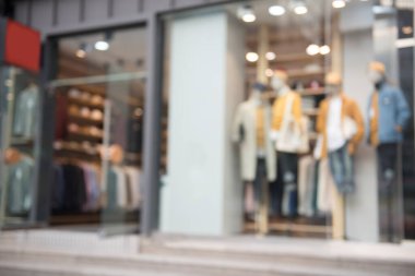 Giysi mağazasının önü bulanık. Arka planda Bokeh kullanımı olan kışlık moda elbisesinde yapay model sergiliyor..