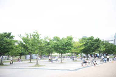 Bulanık Asyalı kalabalık, yaz tatilinde parkta aile aktiviteleri ve şehirde arka plan için yeşil ağaç.